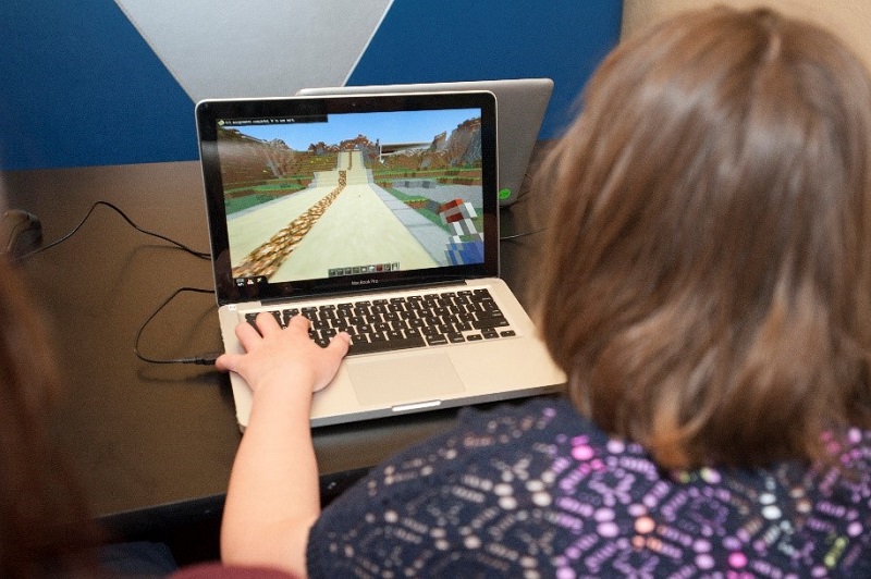 Teen playing Minecraft on laptop
