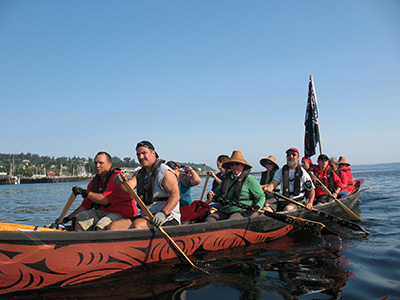 Group of adults rowing a canoe.