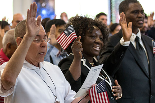 People hold American flags as they take the Oath of Allegiance during a naturalization ceremony at the Gwinnett County Public Library in Georgia.
