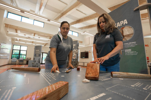 Exhibit visitors stand around an interactive display table.