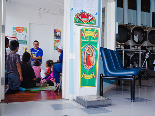 Wash and Learn library, children sitting in a reading circle next to coin laundry machines