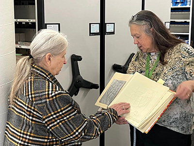 A woman holding a braille book for another patron to read.