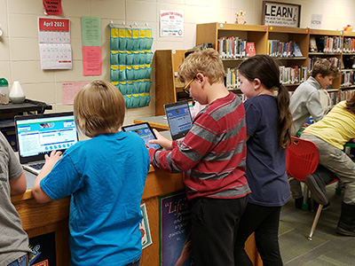Children using laptops and devices in the library