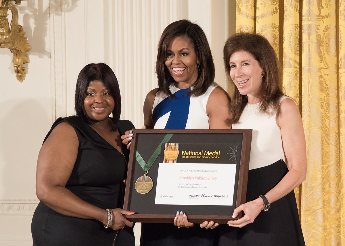 First Lady Michelle Obama presents the award to community member Kim Best and Brooklyn Public Library President and CEO Linda E. Johnson. 