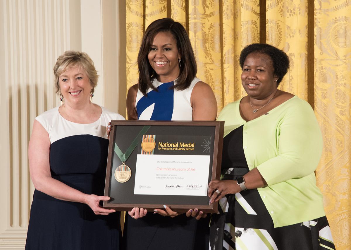 First Lady Michelle Obama presents the award to Columbia Museum of Art Director Karen Brosius and community member Joyce Rose-Harris. 
