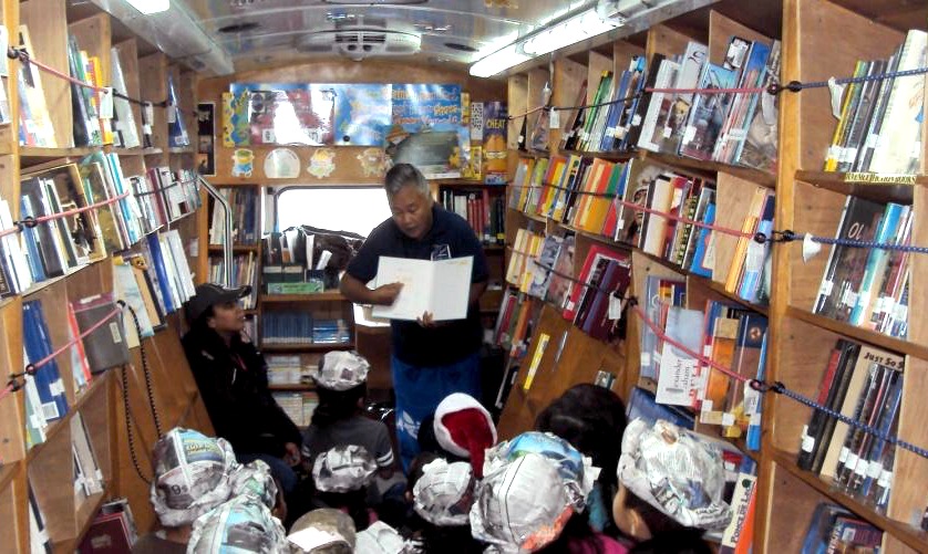 Visitors listen to stories read inside a bookmobile.