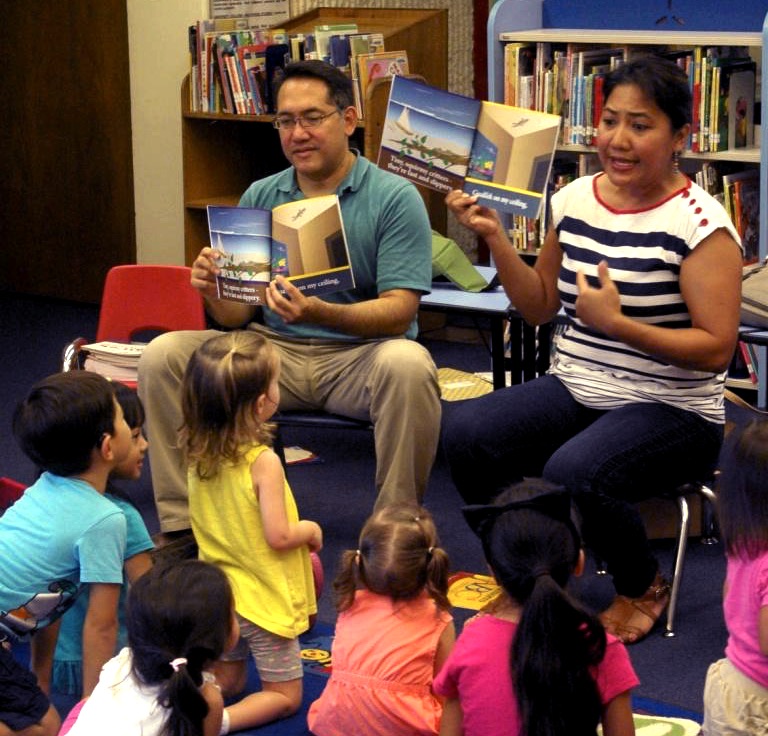 Two adults reading books to children.