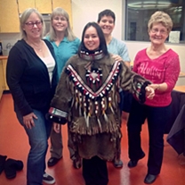museum staff stand behind a student wearing the finished parka