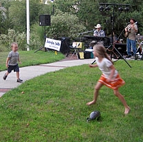 Kids run and play in front of an outdoor musical performance