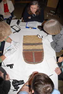 museum sewers examine sewn pieces around a table
