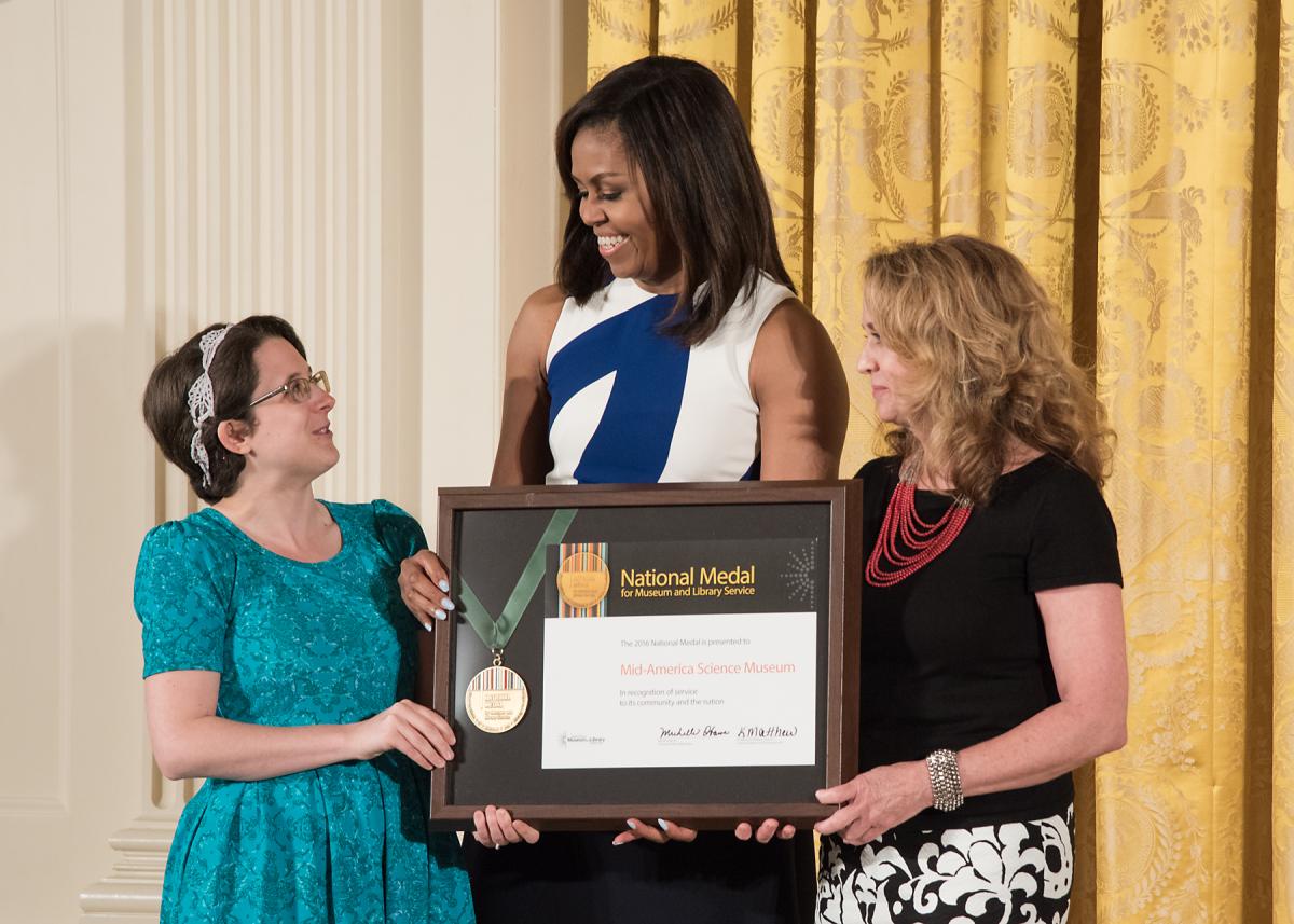 First Lady Michelle Obama presents the award to community member Casey Wylie and Mid-America Science Museum Executive Director Diane LaFollette. 