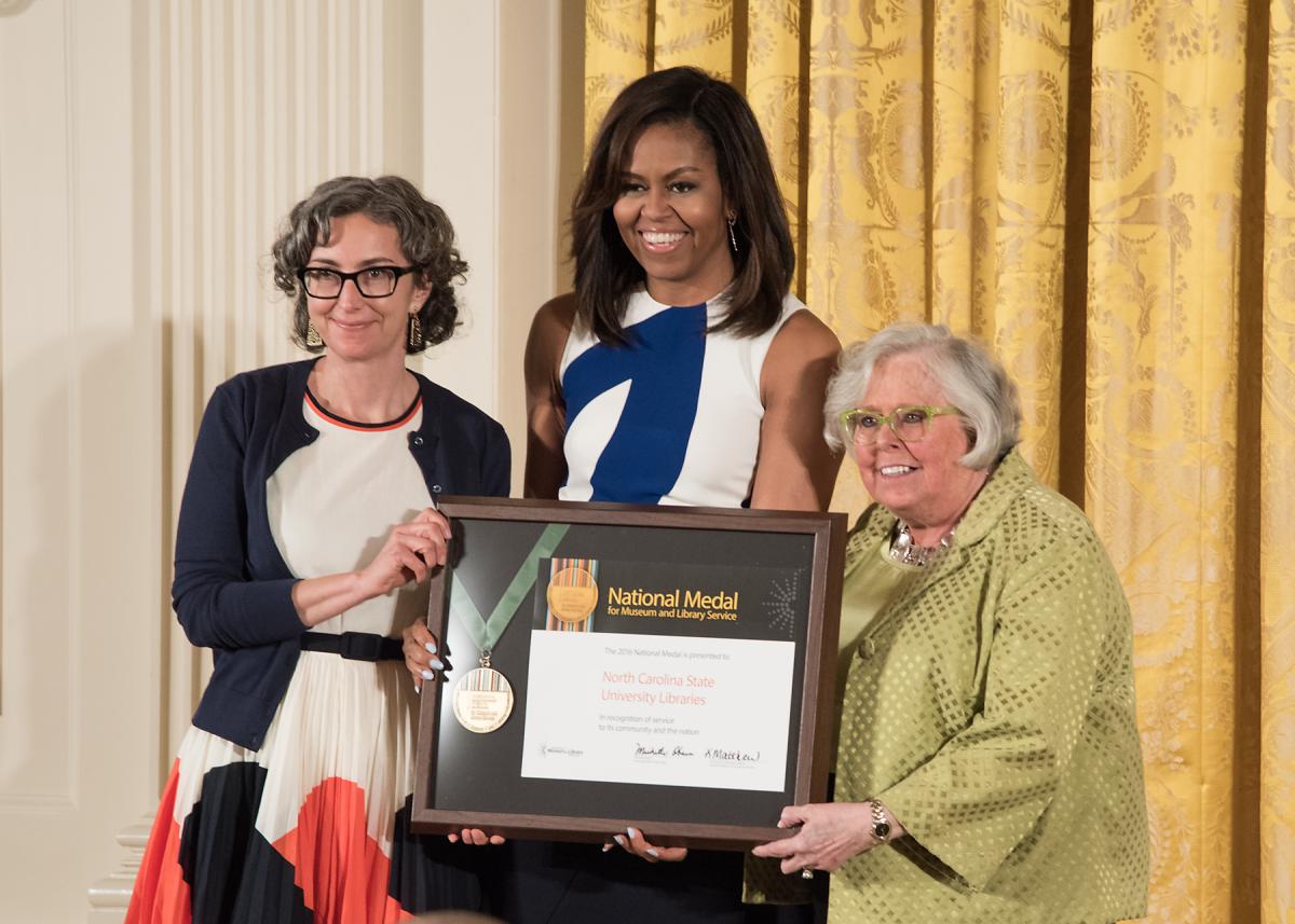 First Lady Michelle Obama presents the award to community member Marsha Gordon and Vice Provost and Executive Director of Libraries for the North Carolina State University Libraries Susan Nutter