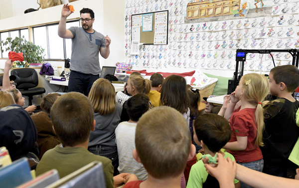 teacher demonstrates to class of elementary-age students