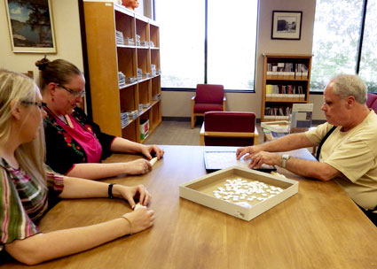 A visually-impaired patron plays Scrabble with library staff