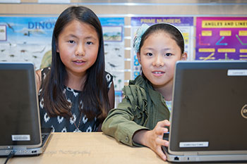 Two girls sitting at a desk with laptops. Photo courtesy of the San Mateo Public Libraries.