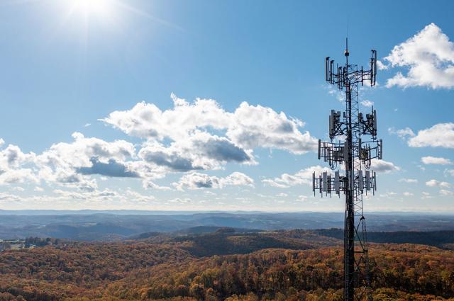 Aerial view of mobile phone cell tower over forested rural area of West Virginia to illustrate lack of broadband internet service. 