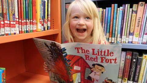 Little girl reading book in library