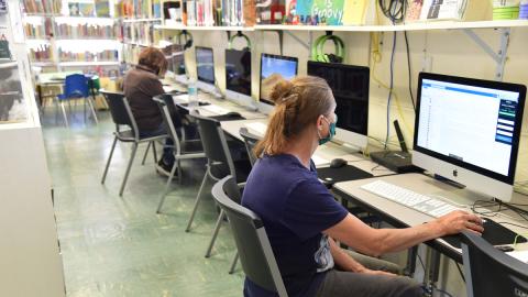 Woman sitting at library computer station.