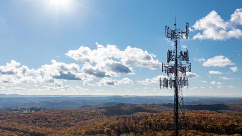 Aerial view of mobile phone cell tower over forested rural area of West Virginia to illustrate lack of broadband internet service. 