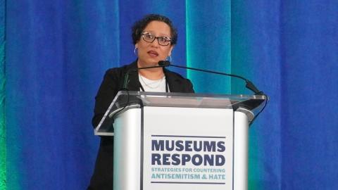 Deputy Director of Museum Services Laura Huerta Migus standing behind podium.