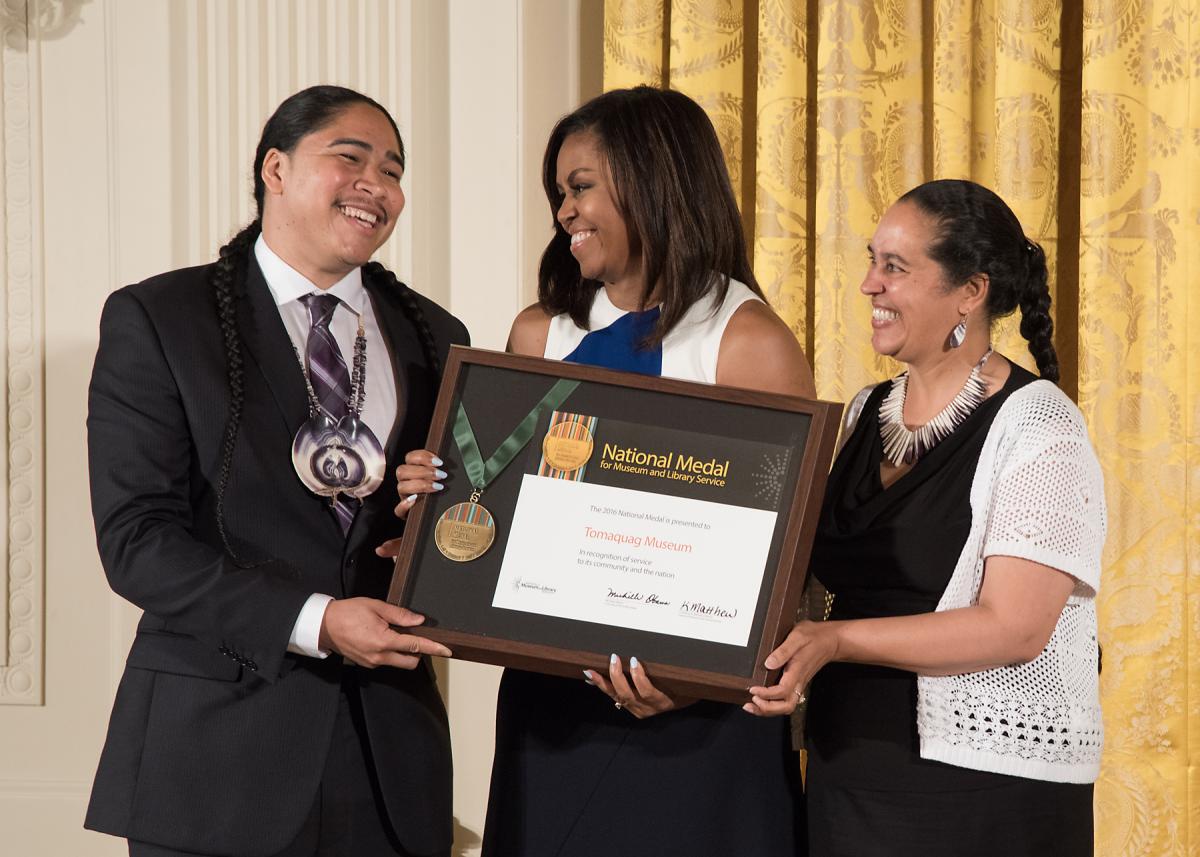 Community member Christian Hopkins celebrates with Tomaquag Museum Executive Director Loren Spears after accepting the award from First Lady Michelle Obama.  