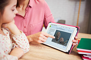 Woman and child sitting at desk with smart device